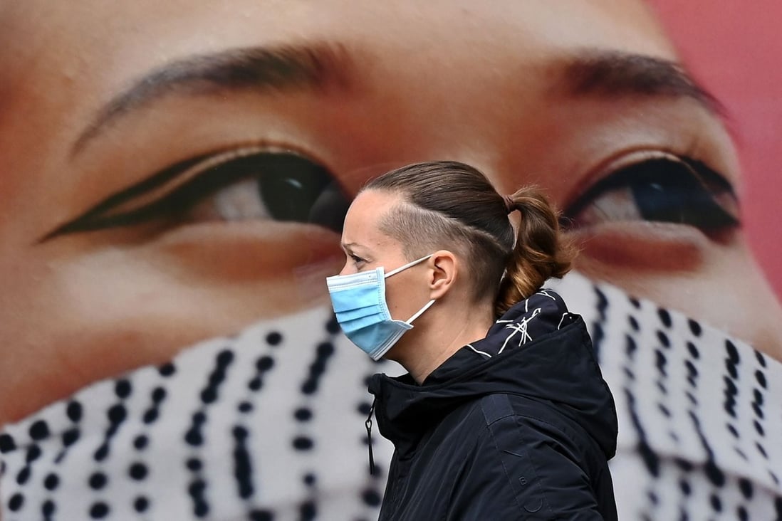 A pedestrian walks past a poster of a person wearing a face covering in West London on October 11. Over the past few months, Europe’s largest economies have been hit by a second wave of infections that is forcing governments to reimpose restrictions. Photo: AFP