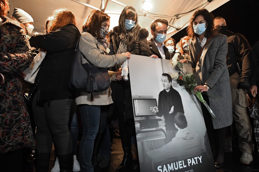 Relatives and colleagues hold a picture of Samuel Paty during a national homage to the late French teacher in Conflans-Sainte-Honorine, northwest of Paris, on Tuesday. Photo: AFP