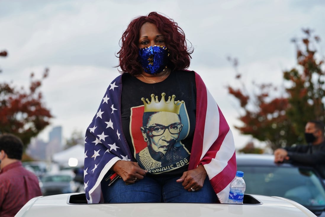 A Joe Biden supporter wrapped in a US flag wearing a late Justice Ruth Bader Ginsburg shirt looks on as former US president Barack Obama campaigns on behalf of Biden in Philadelphia, Pennsylvania. Photo: Reuters