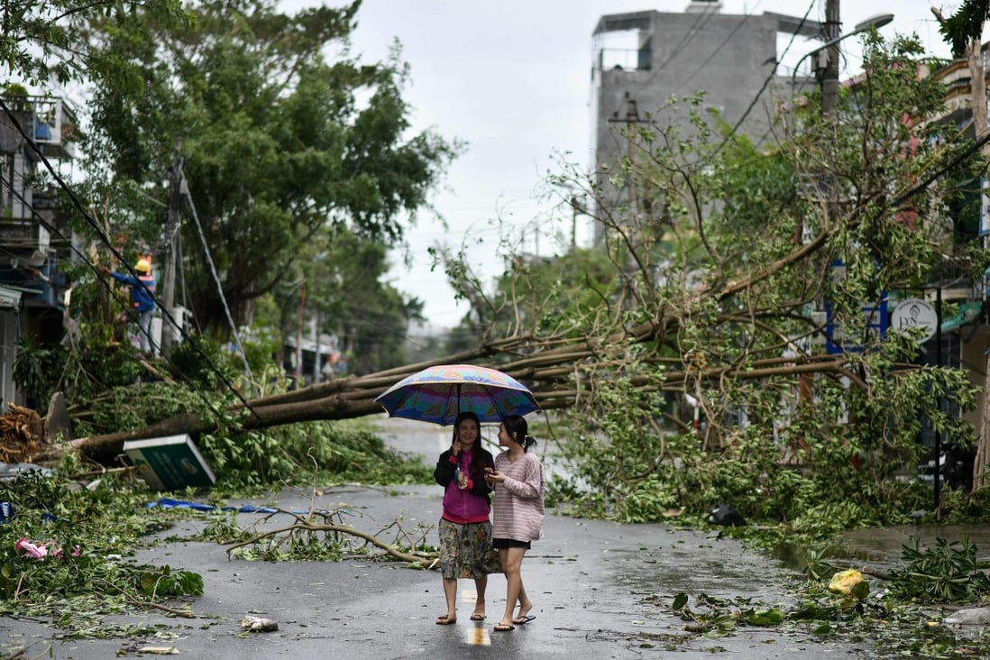 Women walk past uprooted trees in central Vietnam’s Quang Ngai province in the aftermath of Typhoon Molave. Photo: AFP