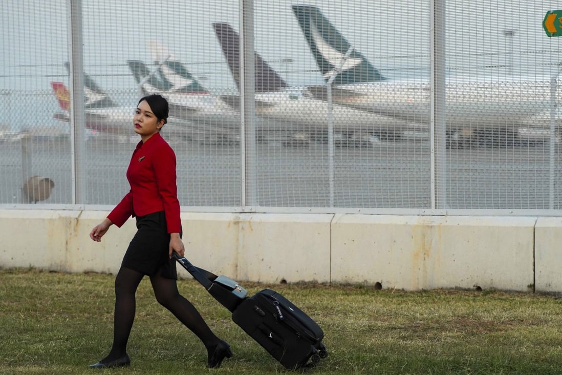 A Cathay Pacific flight attendant wheels her luggage past a parking bay for the company’s aircraft on October 26. Photo: Robert Ng