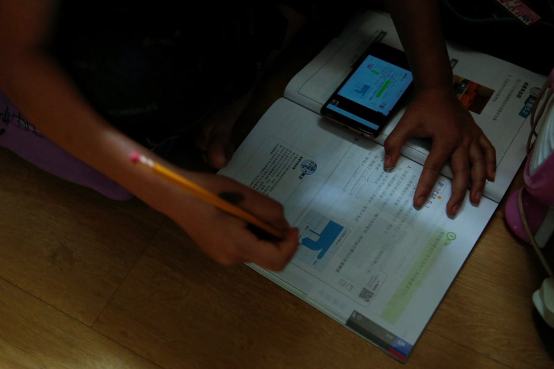 Secondary school student attends an online class with a smartphone at home in Hong Kong during the pandemic. Photo: Reuters