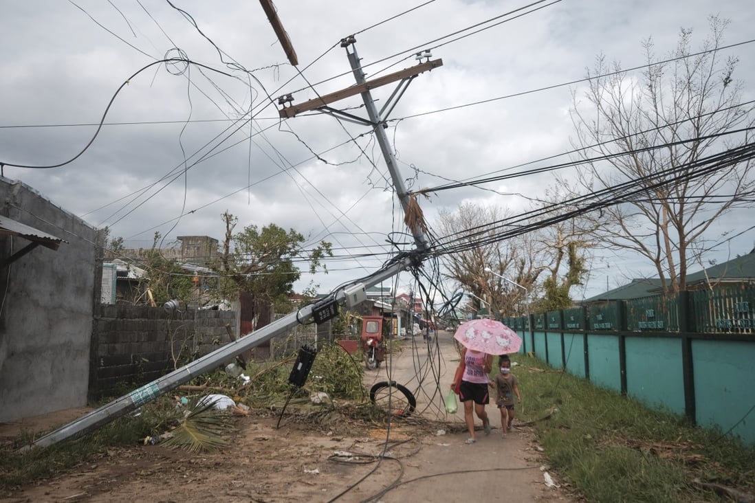 Residents walk under toppled electrical posts in Malilipot, Albay province, central Philippines, after Typhoon Goni. Photo: AP