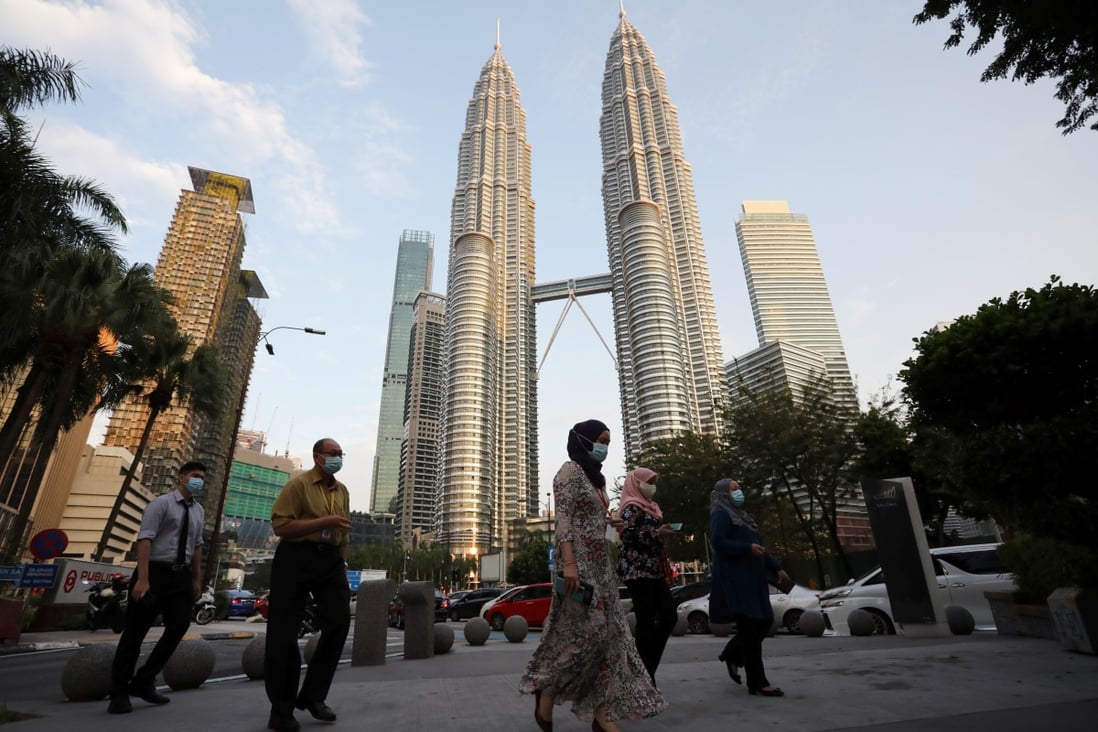 People wearing masks cross a street in front of Petronas Twin Towers in Kuala Lumpur, Malaysia. Photo: Reuters