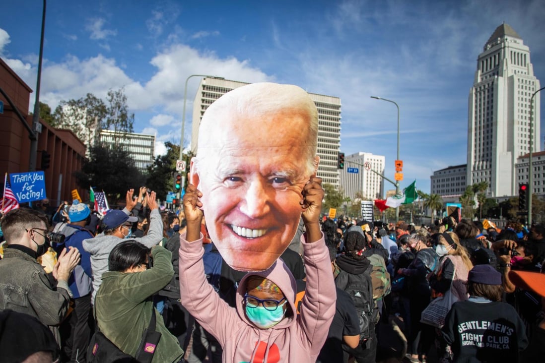 A supporter holds a large cut-out of Joe Biden’s face as people march in Los Angeles to celebrate his election victory on Saturday. Photo: AFP