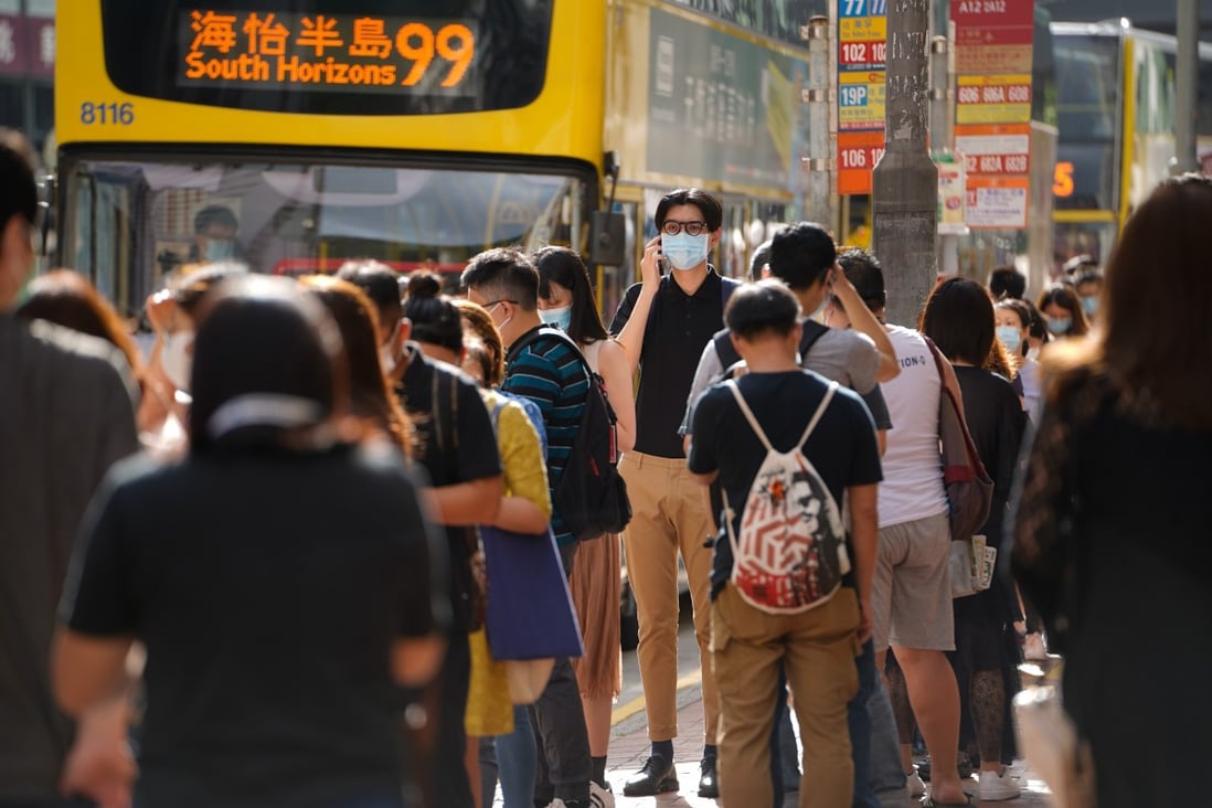 A commuter wearing a protective mask stands in line at a bus stop in Hong Kong. Stocks are getting a jab of optimism as Pfizer unveils promising Covid-19 trial results. Photo: Bloomberg