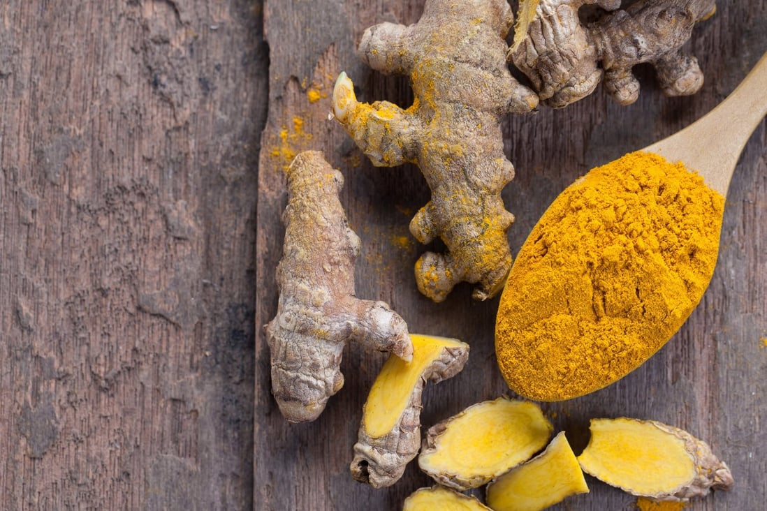 Turmeric powder and turmeric on wooden background. Photo: Shutterstock