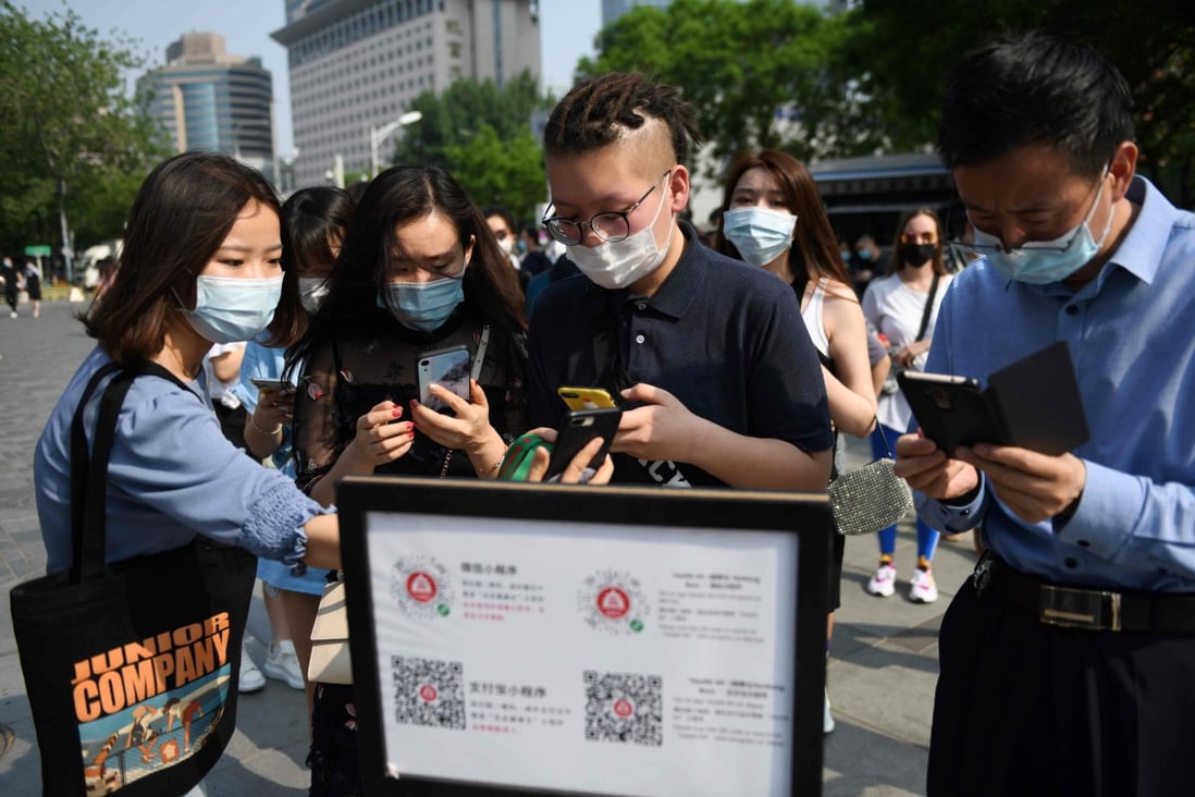Shoppers use a phone app to scan a code to confirm their health and travel status before being allowed to enter a mall in Beijing in May. Photo: AFP