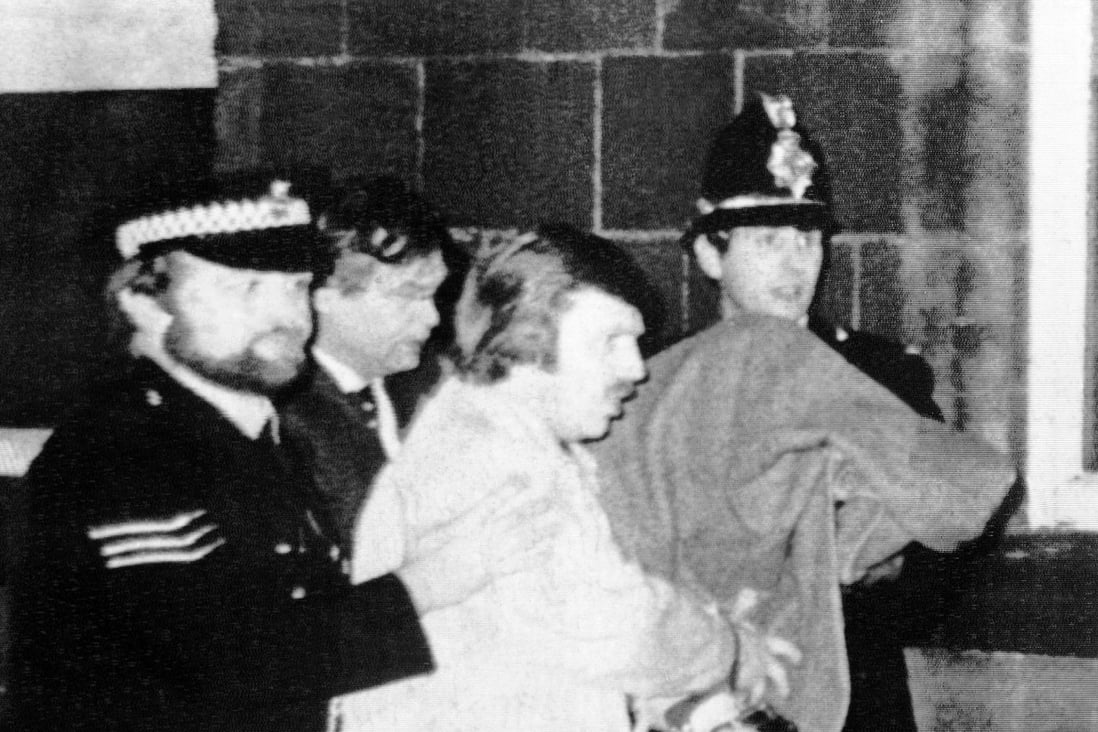 Peter Sutcliffe under a blanket at right being led from Dewsbury Magistrates Court in Dewsbury by police officers in 1981. Photo: AP