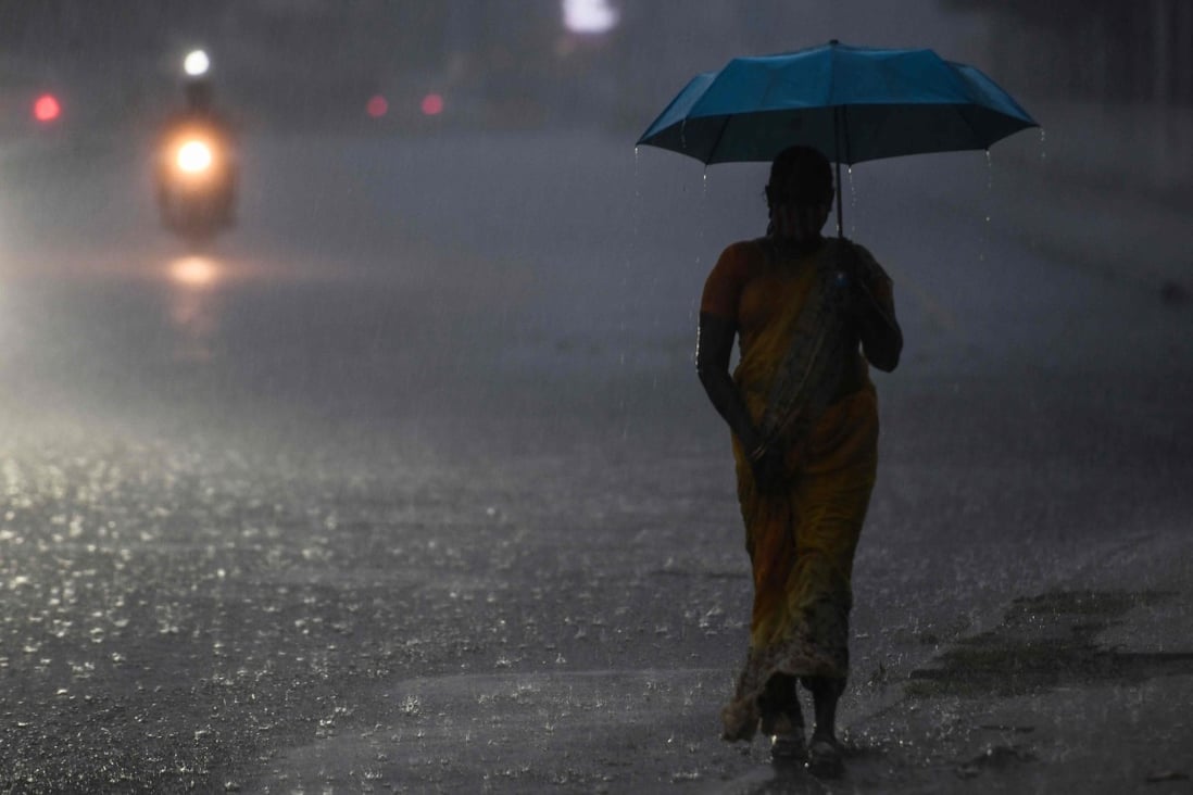 A woman walking alone shelters under an umbrella during heavy rainfall in Chennai. Photo: AFP