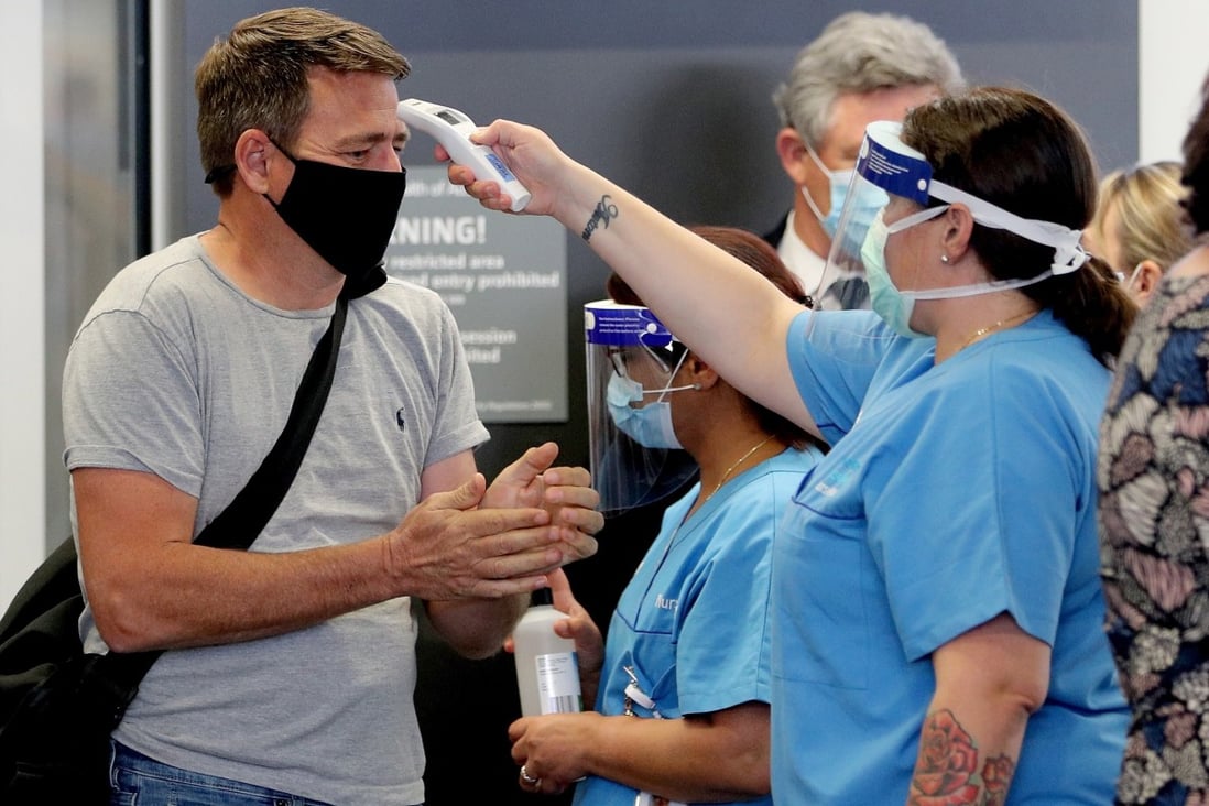 A passenger arriving in Perth from Brisbane has his temperature checked. Australia’s hard border restrictions were eased, as a new coronavirus cluster emerged in South Australia. Photo: EPA-EFE