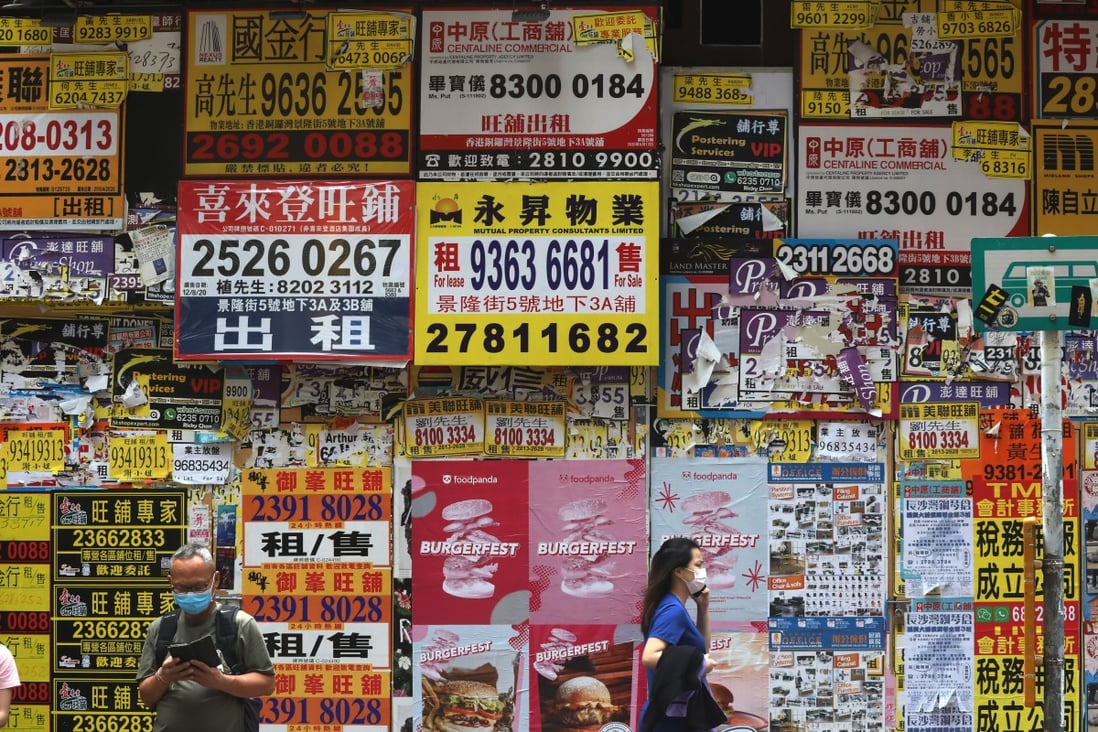 Pedestrians pass a store covered in posters for property agents in Causeway Bay, Hong Kong. Photo: K. Y. Cheng