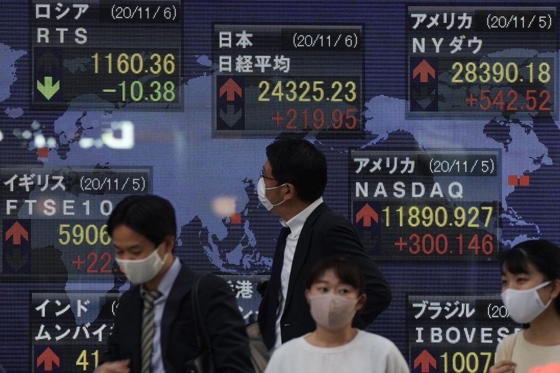 A pedestrian looks at a display showing global stock market information in Tokyo, Japan, on November 6. Photo: EPA-EFE