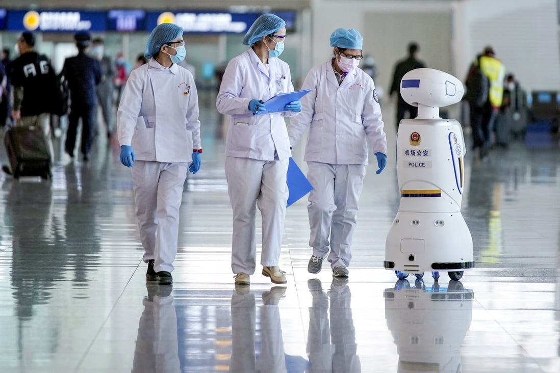 Medical workers walk by a police robot at the Wuhan Tianhe International Airport after travel restrictions on leaving Wuhan were lifted on April 8. Photo: Reuters