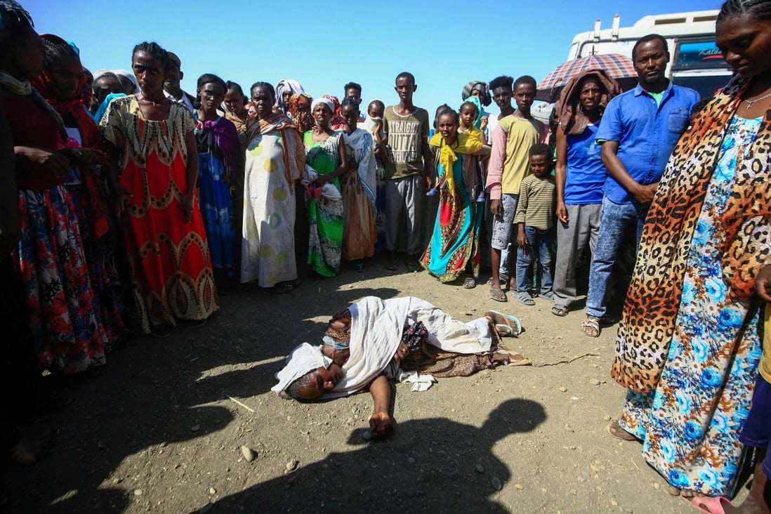Ethiopian refugees who fled fighting in the Tigray region stand around a woman who collapsed at the Village 8 border reception centre in Sudan’s eastern Gedaref state. Photo: AFP