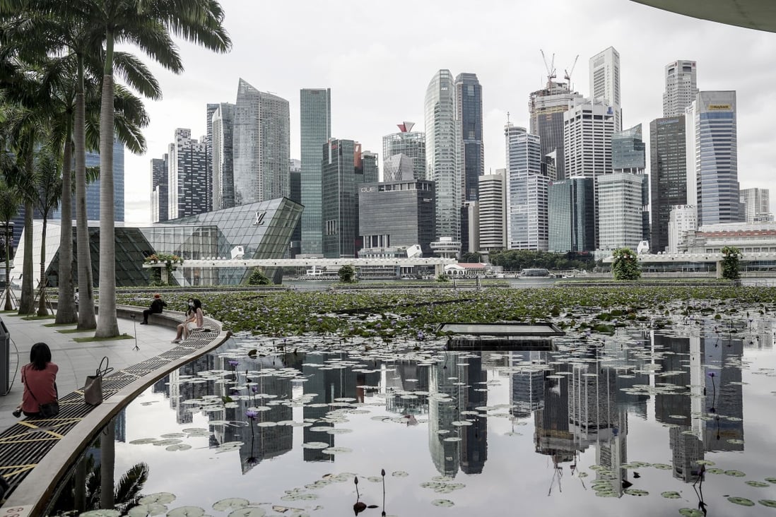 The skyline of Singapore’s financial district reflected in a lotus pond at the ArtScience Museum. Singapore’s economy is on track to return to growth in 2021, the government says. Photo: EPA-EFE