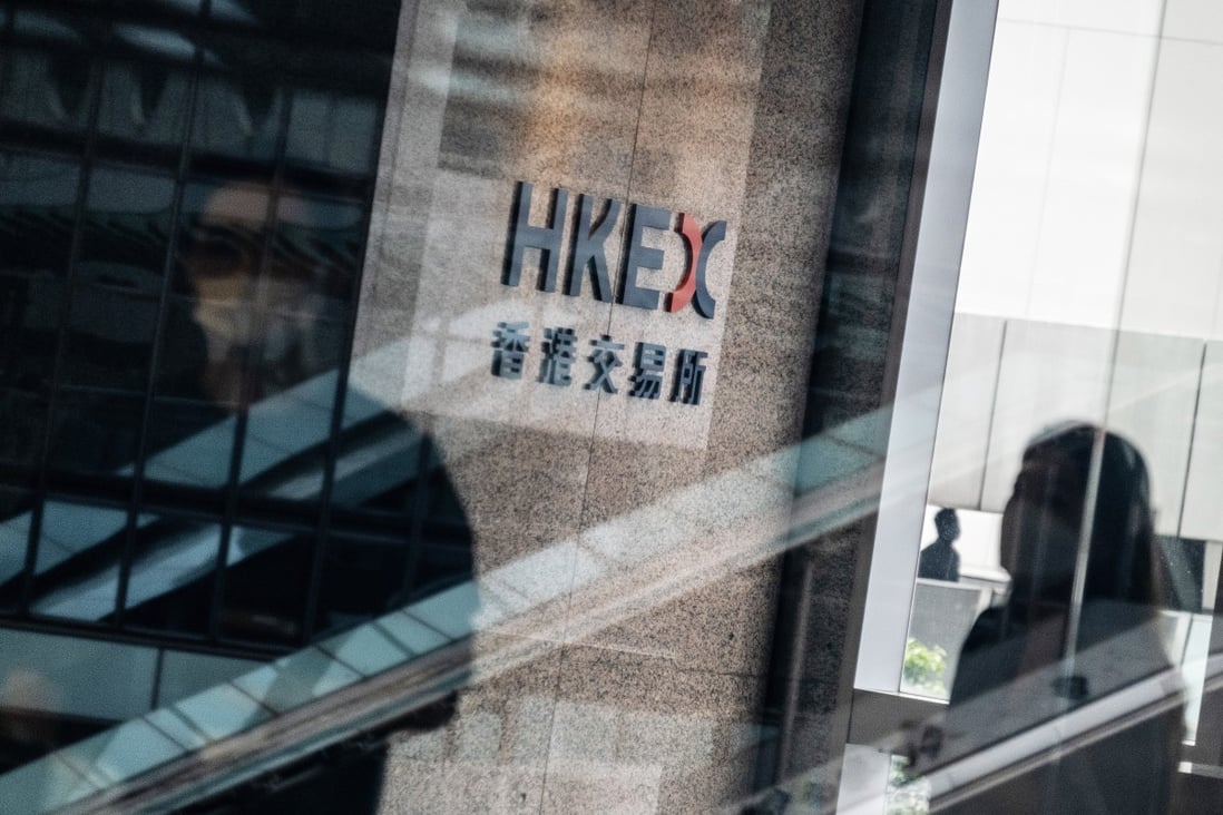 People wearing protective masks walk past signage for Hong Kong Exchanges & Clearingat the Exchange Square complex in Central, Hong Kong. Photo: Bloomberg