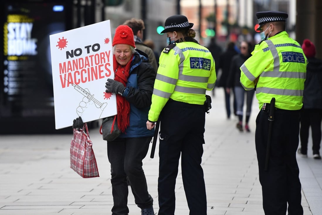 Police officers speak to a protester at an anti-vaccine demonstration outside the offices of the Bill and Melinda Gates foundation in central London on November 24. Photo: AFP