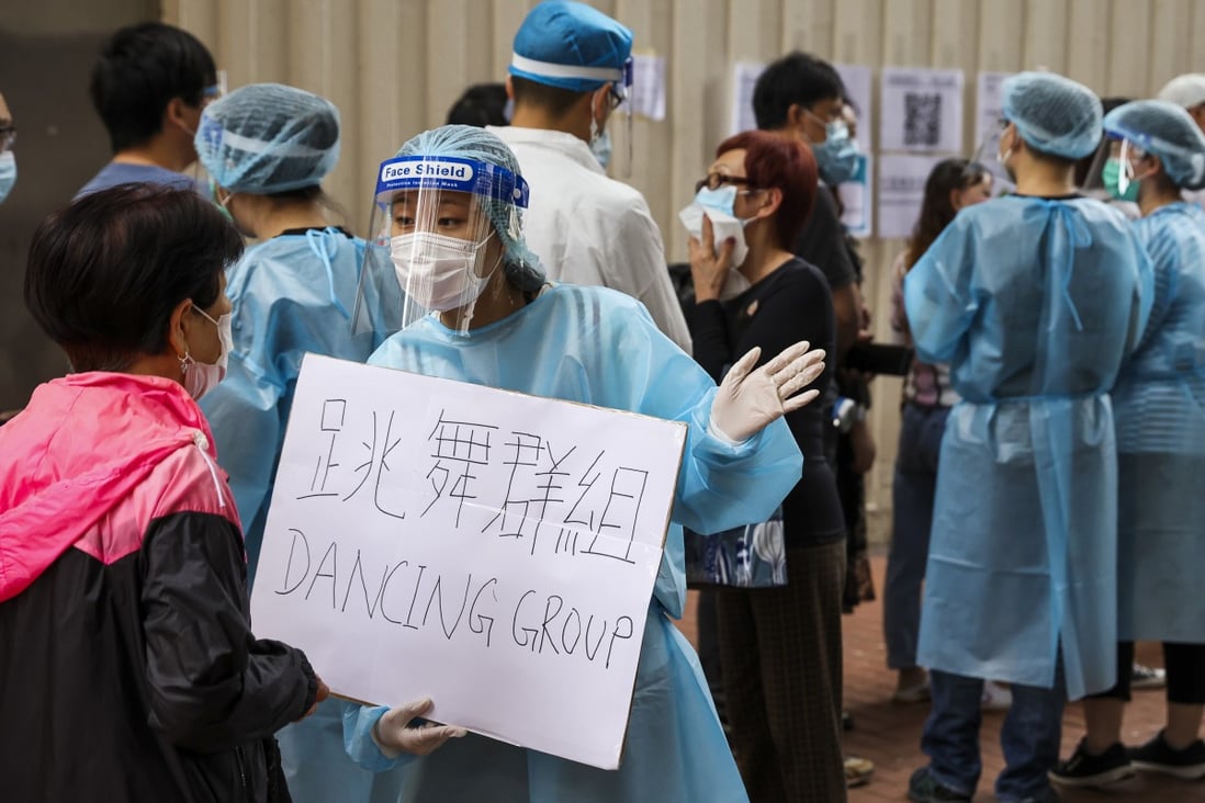 A health care worker holds a sign directing those connected to the “dance studio” cluster at a Covid-19 community testing centre in Yau Ma Tei on November 23. Photo: Nora Tam