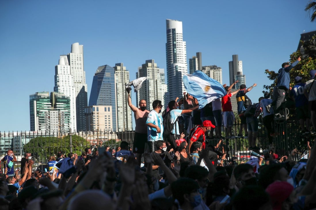 People climb on the fence of the Casa Rosada presidential palace as they gather to mourn the death of soccer legend Diego Maradona in Buenos Aires on Thursday. Photo: Reuters