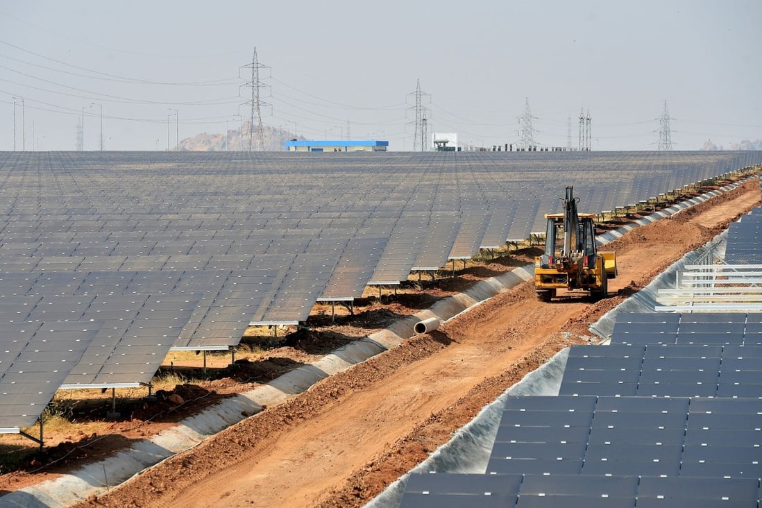 An earth mover passes amid rows of solar panels at “Shakti Sthala”, the 2000 Megawatt solar power park in Pavagada Taluk, situated about 150 kms from Bangalore, India. Photo: AFP