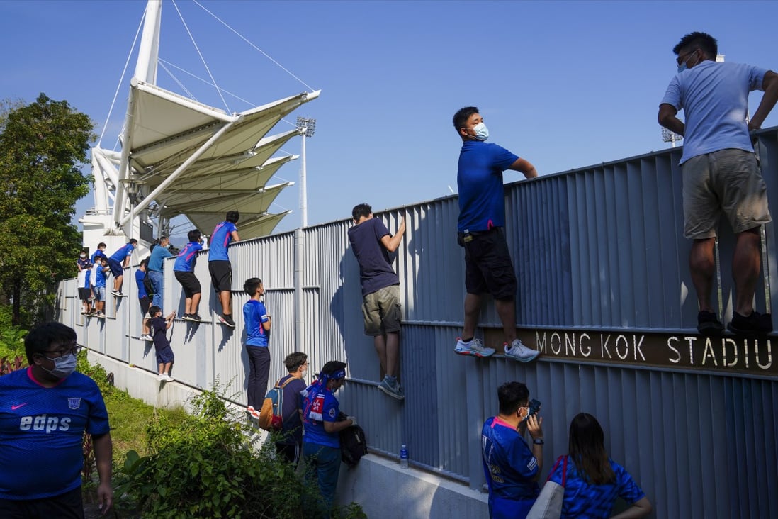 Football fans try to get a glimpse of a match between Happy Valley and Kitchee at Mong Kok Stadium as social gathering rules ban crowds again. Photo: Sam Tsang