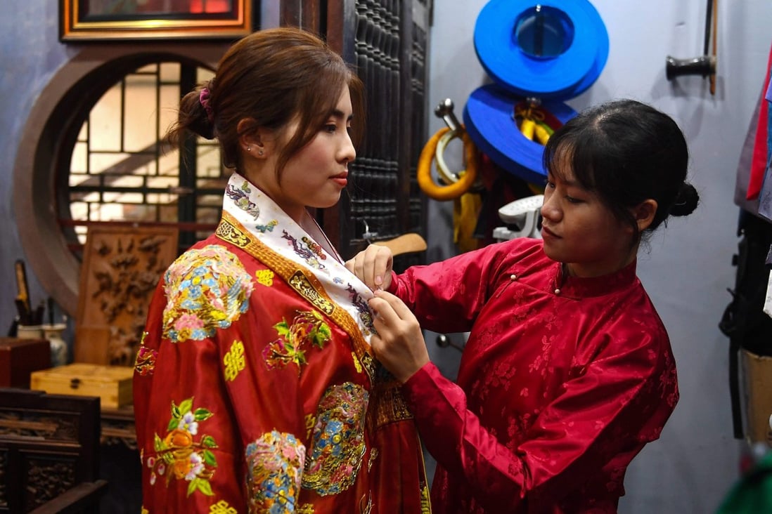 Pham Trang Nhung (left) tries on an outfit based on traditional Vietnamese patterns and styles at the Y Van Hien company studio in Hanoi. Photo: AFP