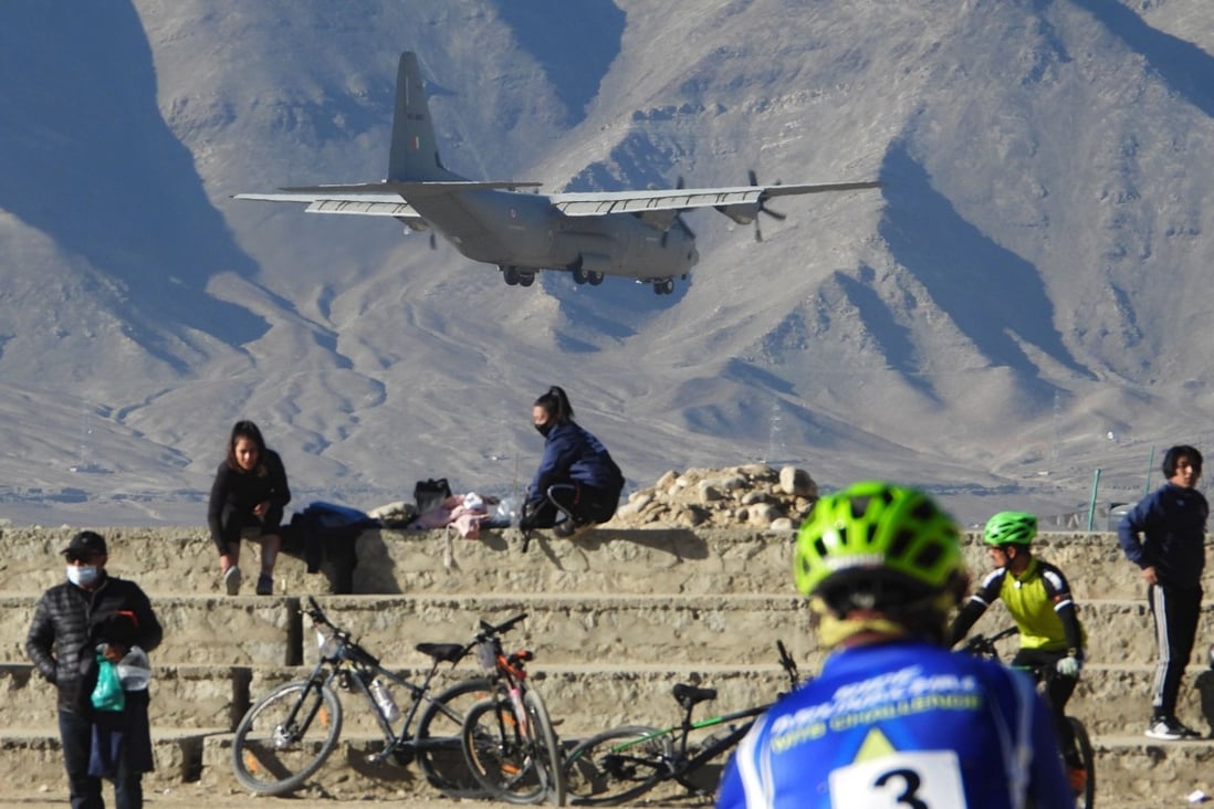 An Indian Air Force aircraft flies past cyclists near a mountain range in Leh, the joint capital of the union territory of Ladakh bordering China. Photo: AFP