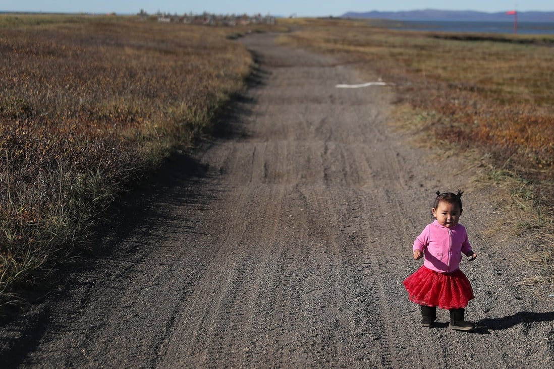 A one-year-old girl walks along a road in the Alaskan village of Kivalina, which is being swallowed by rising oceans, on September 13, 2019. Photo: Getty Images/AFP