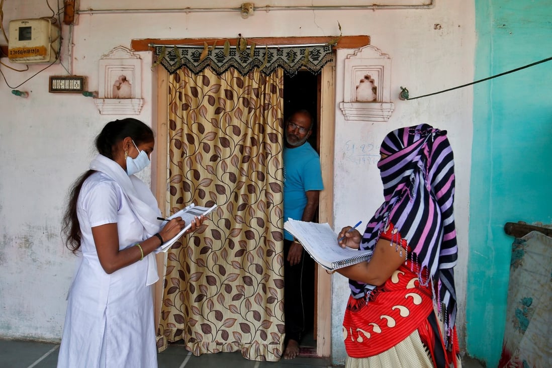 Health workers conduct a door-to-door survey for the first shot of Covid-19 vaccine for people older than 50 years and with co-morbidities in a village on the outskirts of Ahmedabad, India, on December 14. Photo: Reuters