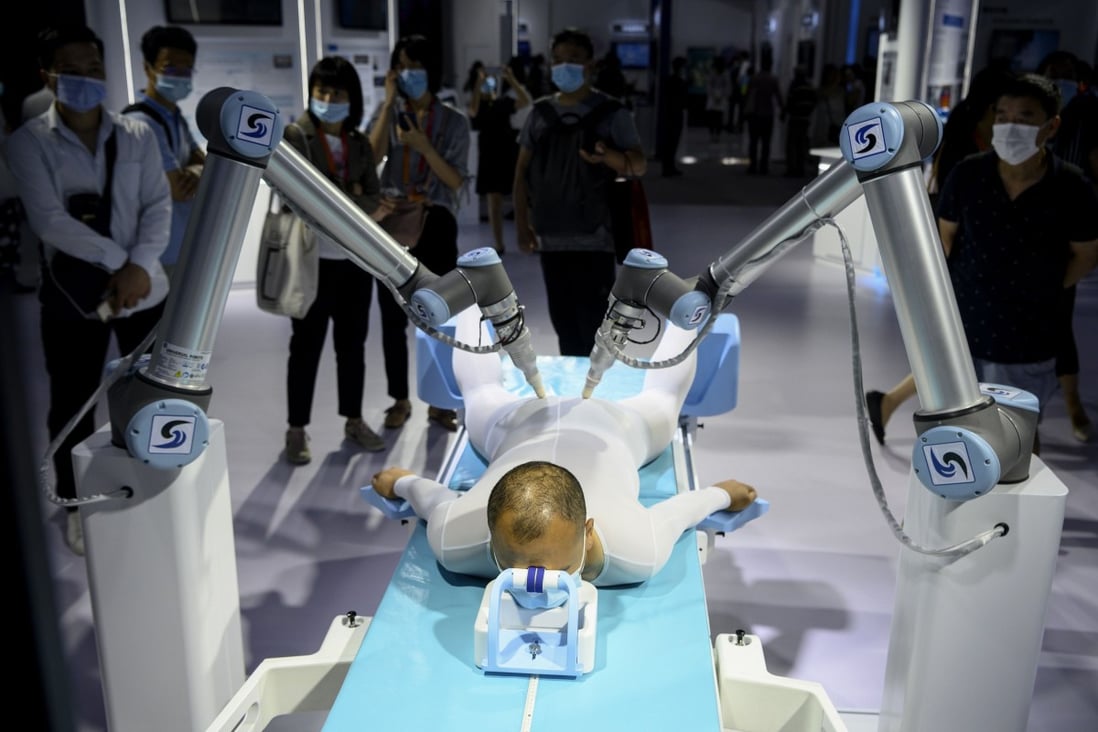 A man tries out a Chinese traditional medicine treatment using robotic arms at the China International Fair for Trade in Services in Beijing on September 6. AI-driven automation will transform almost every service job in some way, but they will replace very few because there’s always something that “globotics” can’t do. Photo: AFP