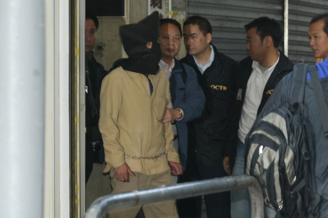 Police escort a hooded suspect, thought to be Kwai Ping-hung, out of a building in Yau Ma Tei on December 24, 2003. Photo: SCMP