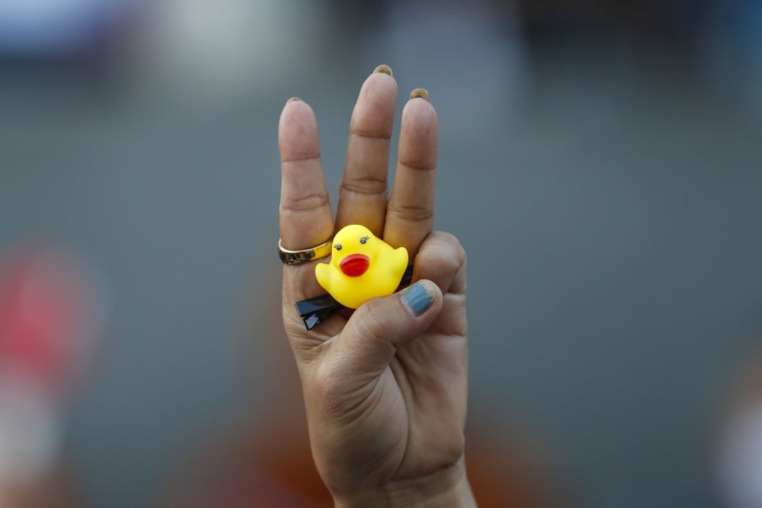 The three-finger protest gesture is flashed by a demonstrator holding a yellow duck, which has become a good-humoured symbol of resistance during anti-government rallies in Thailand. Photo: AP