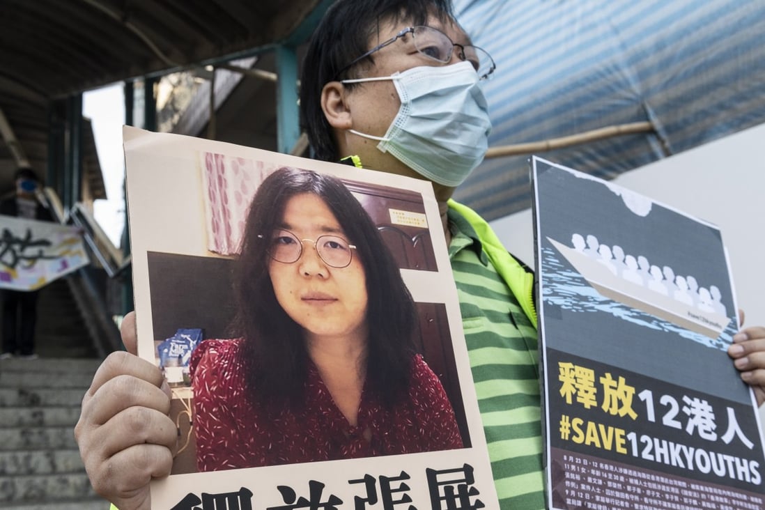 A pro-democracy activist holds up signs in support of Zhang Zhan and the 12 detainees arrested at sea outside Beijing’s liaison office in Hong Kong on Monday. Photo: EPA-EFE