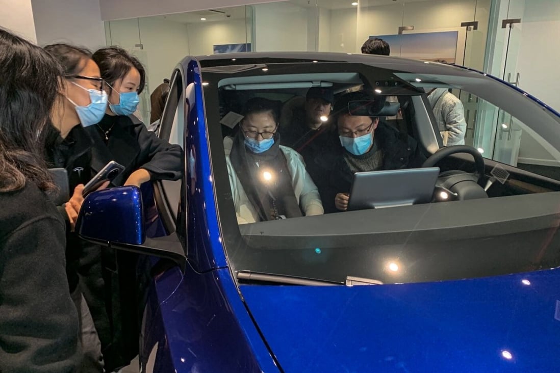 Customers at a Tesla showroom on Shibo Avenue in Shanghai's Pudong district take a close look at the locally built Model Y on Sunday. Photo: Daniel Ren