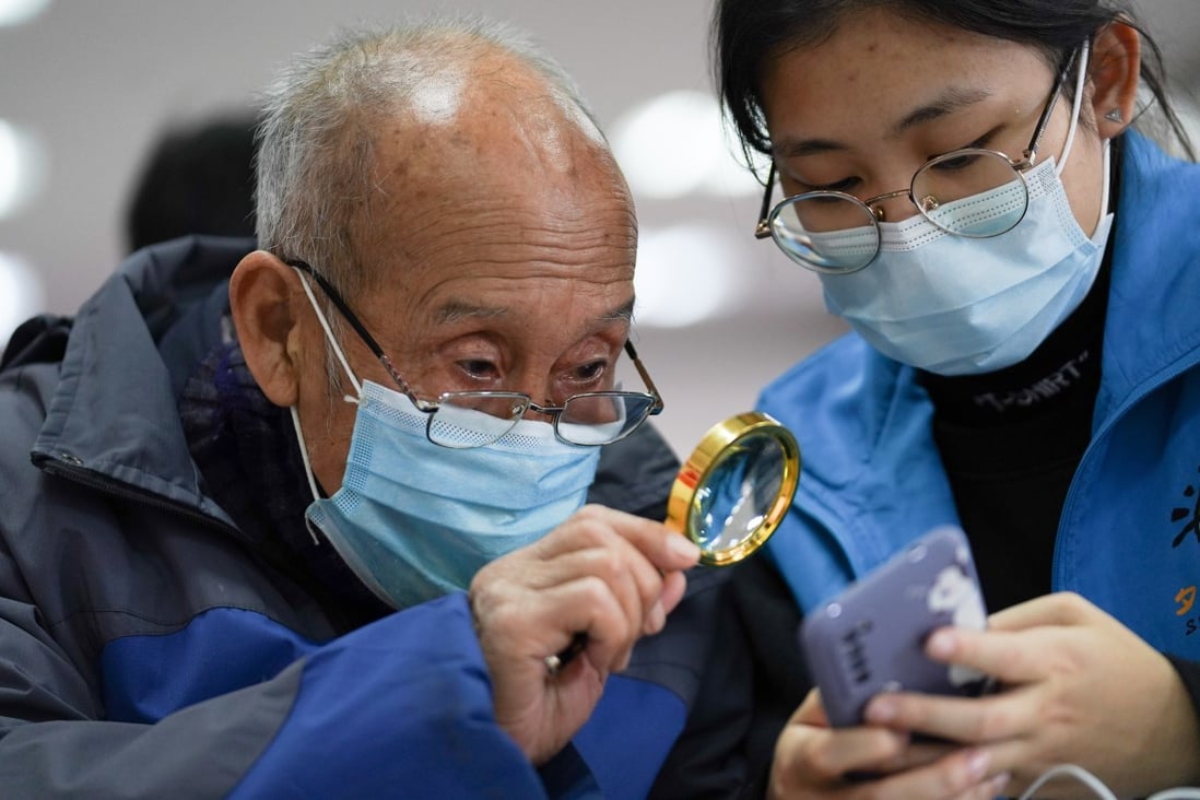 A student volunteer shows a senior resident how to make a hospital appointment using mobile phone at a community activity centre in Beijing on December 8, 2020. Photo: Xinhua