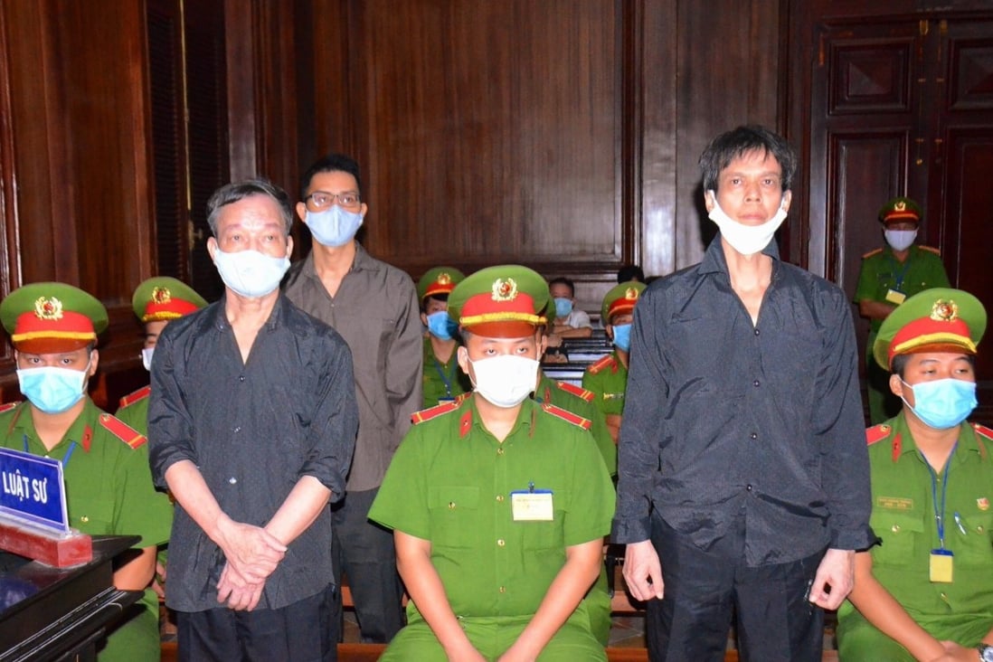 Vietnamese journalists Pham Chi Dung, right, Le Huu Minh Tuan, centre back, and Nguyen Tuong Thuy, left, stand between police during their trial in Ho Chi Minh City. Photo: EPA