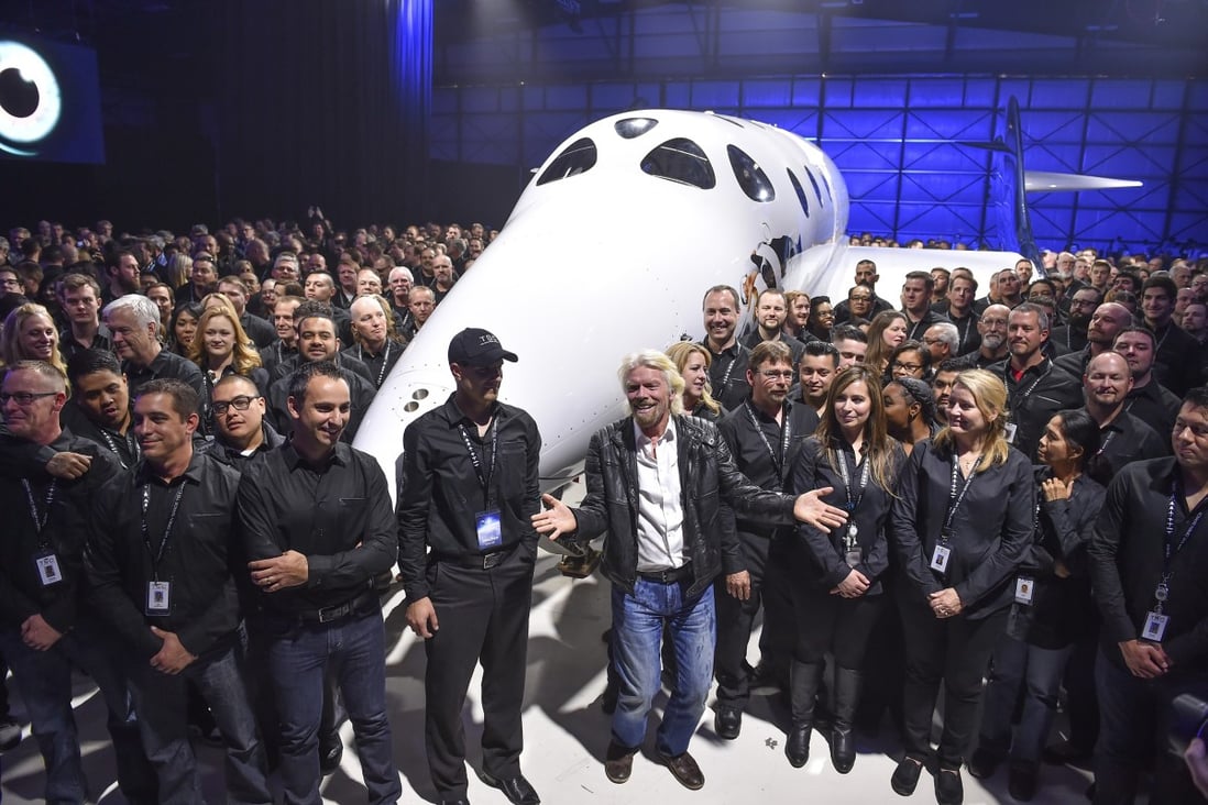 Virgin Galactic's Richard Branson (front, centre) gathers with Virgin Galactic employees in front of the SpaceShip Two VSS Unity after a roll-out ceremony. The company is set to begin commercial space flights this year. Photo: Getty Images