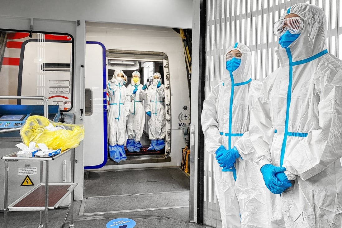 Cabin crew dressed in PPE await passengers before a flight from Amsterdam to China during the pandemic. Photo: Justin Jin
