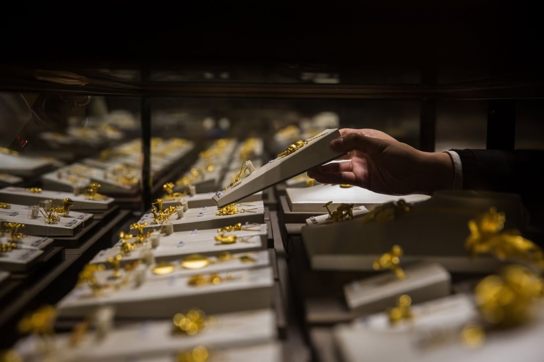 An employee handles a gold jewellery set inside a display case at a Chow Tai Fook shop in Hong Kong. The gold and jewellery retailer has more than 4,000 outlets worldwide. Photo: Bloomberg