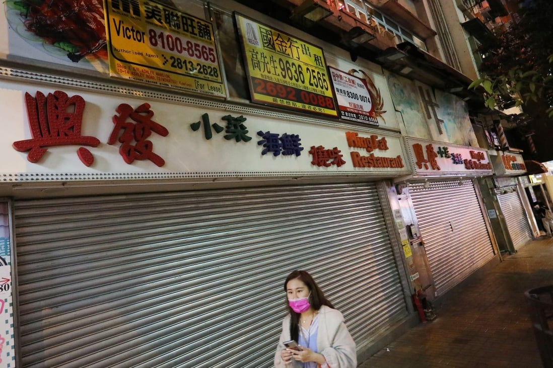 A woman in a mask walks past a row of closed shops on Ashley Road in Hong Kong’s Tsim Sha Tsui. Photo: Nora Tam