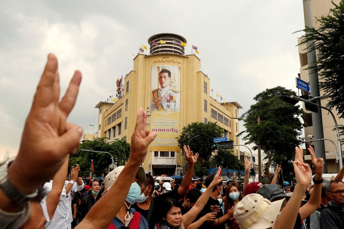 Pro-democracy demonstrators give a three-finger salute while marching against the backdrop of a portrait of King Maha Vajiralongkorn in Bangkok. Photo: Reuters