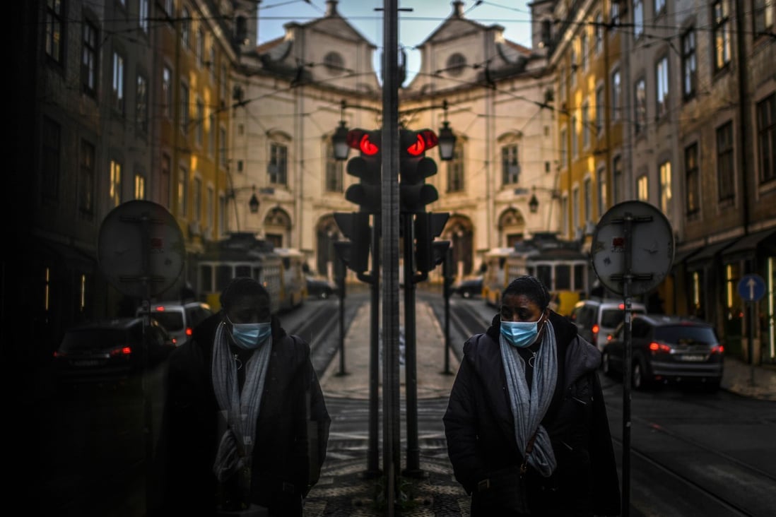 A woman wearing a face mask is reflected on a shop window while walking in Lisbon, Portugal. Photo: AFP