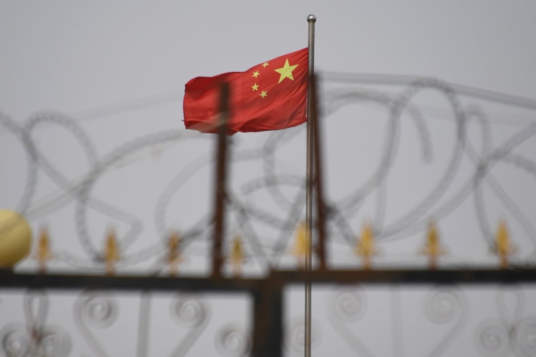 The Chinese flag behind razor wire at a housing compound in Yangisar, south of Kashgar, in China’s western Xinjiang region. Photo: AFP