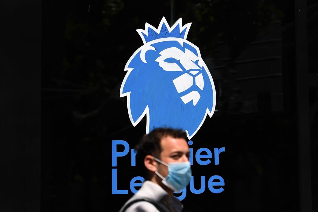 A man wearing a protective mask walks past the English Premier League logo in London in May ahead of football resuming in June. Photo: EPA