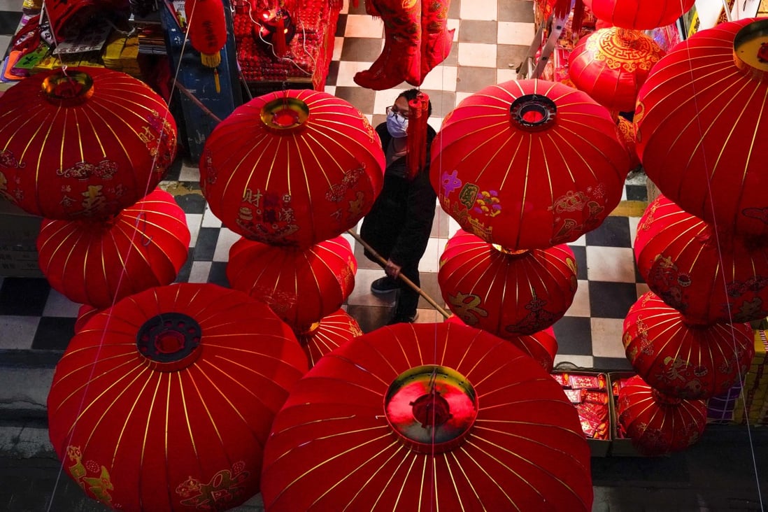 A vendor of Lunar New Year decorations looks up near giant lanterns hung outside a store ahead of the Year of the Ox Chinese Lunar New Year celebrations in Wuhan in central China's Hubei province. Photo: AP Photo