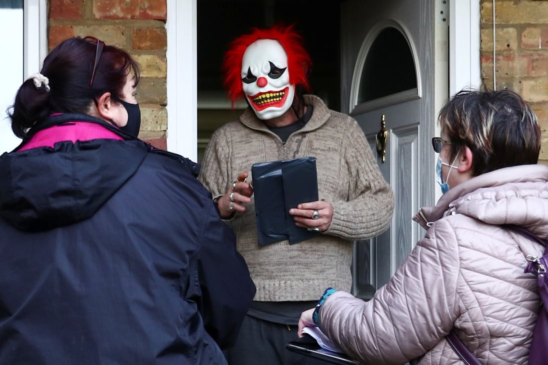 Volunteers hand out a Covid-19 home test kit to a resident wearing a clown mask in Woking, Britain on Tuesday. Photo: Reuters