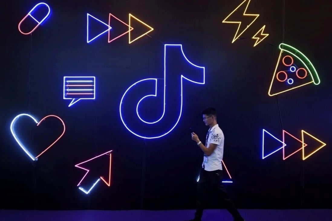 A man holding a phone walks past a logo for ByteDance’s app TikTok, known locally as Douyin, at the International Artificial Products Expo in Hangzhou. Photo: Reuters