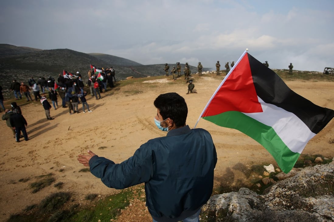 A protester holds a Palestinian flag during a protest against the expansion of Jewish settlements in the West Bank village of Beit Dajan, east of Nablus, on Friday. Photo: Xinhua