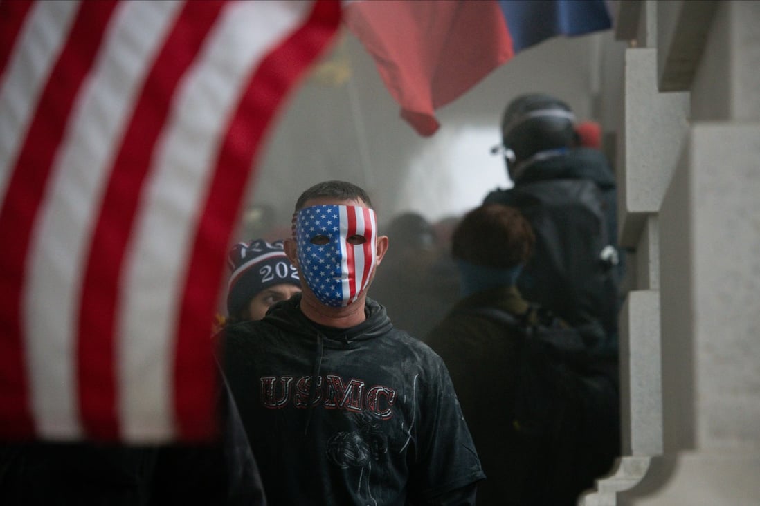 A demonstrator wears an American flag mask during a protest at the US Capitol in Washington on January 6. The obsessive conviction of Donald Trump and his followers about US election fraud took contrarianism to excessive extremes. Photo: Bloomberg